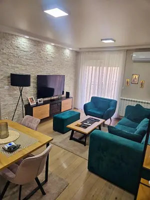 a living room with blue furniture and a flat screen tv at Lux apartmann in Karaburma