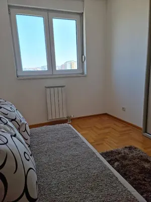 an empty bedroom with two windows and a rug at Vels Suite in Voždovac
