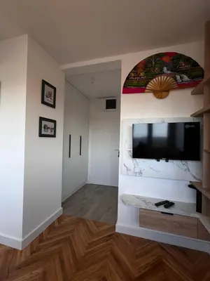 a living room with a flat screen tv on a wall at Berenji Lux Apartment in Fontana