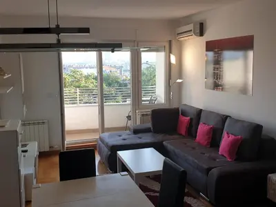 a living room with a couch and a table at Perla, family apartment with parking in Belgrade