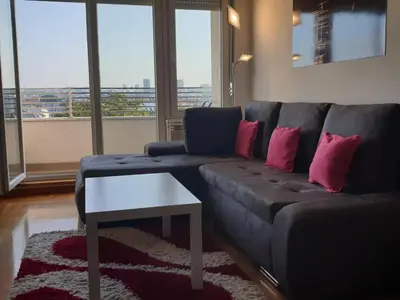 a living room with a blue couch with pink pillows at Perla, family apartment with parking in Belgrade