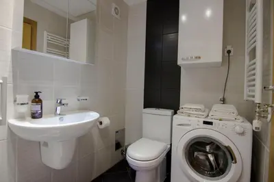 a white bathroom with a sink and a washing machine at Perla, family apartment with parking in Belgrade