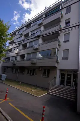 a large white building with stairs in a parking lot at Perla, family apartment with parking in Belgrade