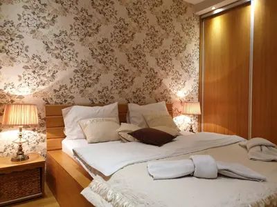 a bedroom with a large white bed with floral wallpaper at Shabby Chik, cozy apartment near St Sava Temple in Belgrade