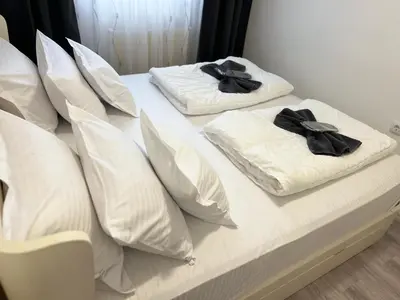 two white pillows on a bed with black bows at Apartman Kutak in Belgrade