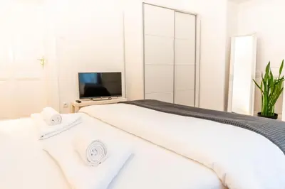 a white bedroom with a bed and a tv at Central and Comfy 2BDR apartment near Parliament in Belgrade