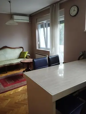 a living room with a table and chairs and a clock at Luna in Vračar (historical)