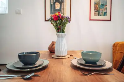 a wooden table with two bowls and a vase with flowers at King Residences City Center in Belgrade