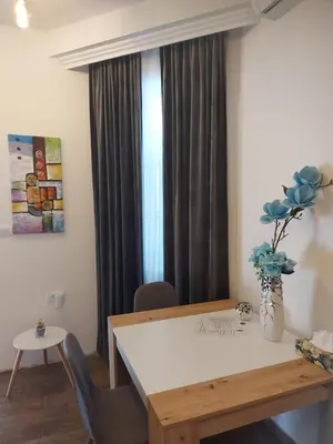 a dining room table with chairs and a vase with flowers at Stan na dan PREMIUM 1 Obrenovac in Obrenovac