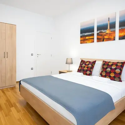 a bedroom with a large bed with a painting on the wall at 3 BDR for 6 CENTER CLOSE TO NATIONAL MUSEUM in Belgrade