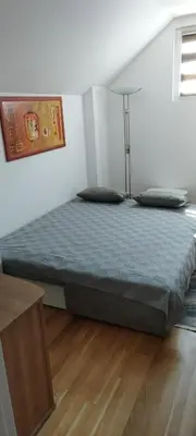 a large bed in a bedroom with a wooden floor at apartman Elena in Zemun