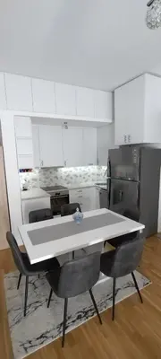 a kitchen with a table and chairs and a refrigerator at apartman Elena in Zemun