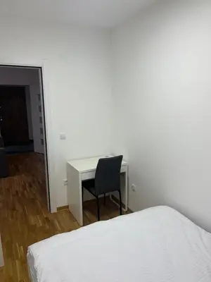 a bedroom with a desk and a chair next to a bed at Apartman Katarina in Pančevo