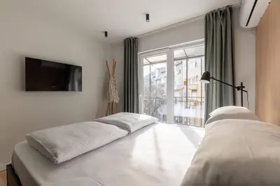 a bedroom with two beds and a large window at HostGost Selected Suites - Skadarlija Artisan in Belgrade