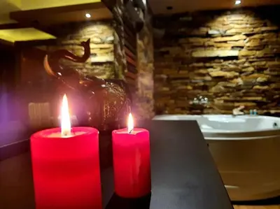 two red candles sitting on a table in a bathroom at Stone Spa Apartman in Sremčica