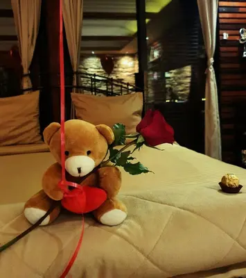 a teddy bear sitting on top of a bed at Stone Spa Apartman in Sremčica