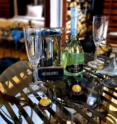 a glass table with a bottle of wine and glasses at Stone Spa Apartman in Sremčica
