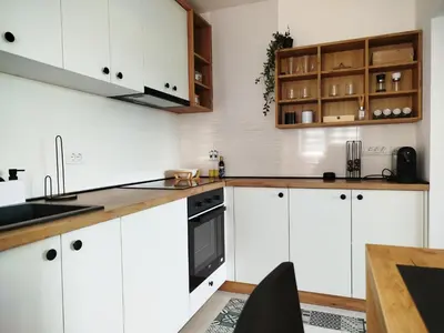 a kitchen with white cabinets and a wooden table at Apartman Alfa in Smederevo