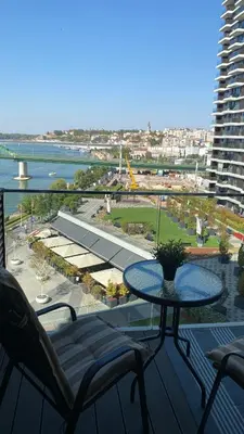 a table on a balcony with a view of a building at BW Residences - Belgrade Waterfront in Sajmište