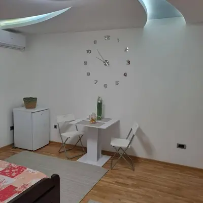 a room with a table and a clock on the wall at Apartman Vojvoda in Sajmište