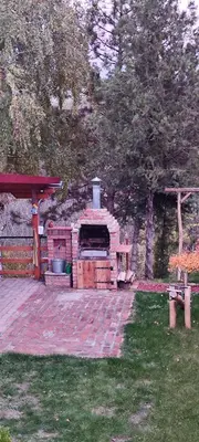 a brick grill in a yard next to trees at Mali Raj in Beška