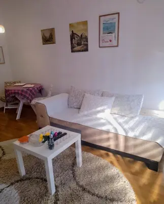 a living room with a white couch and a table at Dora Apartman in Mirijevo