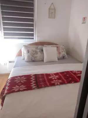 a bed with pillows and a blanket on it at Dora Apartman in Mirijevo