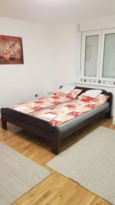 a bed sitting in a room with two rugs at Apartman Vojvoda 1 in Sajmište