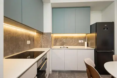 a kitchen with white cabinets and a black refrigerator at Belgrade Waterfront Apartments - Libera in Belgrade