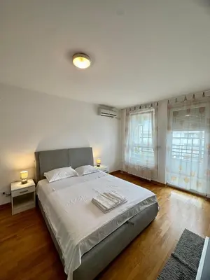 a bedroom with a large bed and two windows at Bellvil 55 in Belgrade