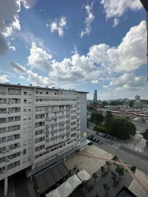 a large white building in a city with a cloudy sky at Bellvil 55 in Belgrade