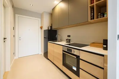 a kitchen with wooden cabinets and a black refrigerator at Waterfront Cosy Studio Nest in Sajmište