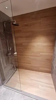 a shower with a wooden wall in a bathroom at Waterfront Cosy Studio Nest in Sajmište