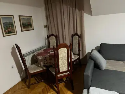 a living room with a table and chairs and a couch at Apartman 1 in Krnjača