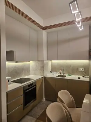 a kitchen with white cabinets and a sink and chairs at BwMils Apartment in Belgrade