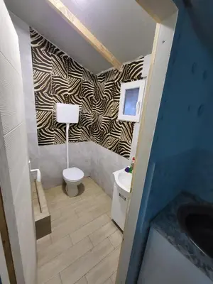 a bathroom with a toilet and a tv on a wall at Pool House 365 in Pe°ani