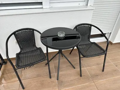 a black table and two chairs with a clock on it at MM Apartman in Stara Pazova