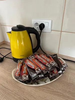 a plate with a yellow tea kettle and packets of chocolate at MM Apartman in Stara Pazova