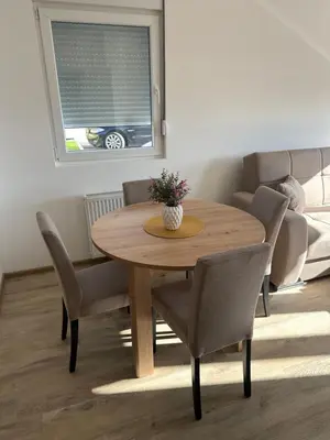 a wooden table and chairs in a living room at MM Apartman in Stara Pazova