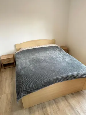 a bed with a wooden frame in a room at MM Apartman in Stara Pazova