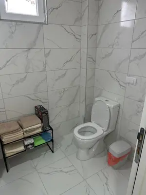 a bathroom with a toilet and a marble wall at MM Apartman in Stara Pazova