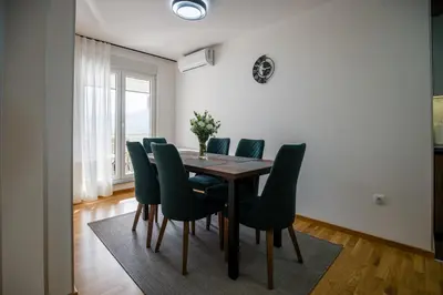 a dining room with a wooden table and green chairs at TOP VIEW apartment 43 in Arandjelovac