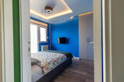a bedroom with a bed with a blue wall at Hram Vracar in Belgrade