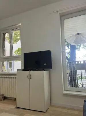 a tv on top of a cabinet in a room with a window at Kopernikova Studio in Belgrade