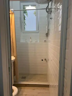 a bathroom with a shower with a toilet and a window at Kopernikova Studio in Belgrade