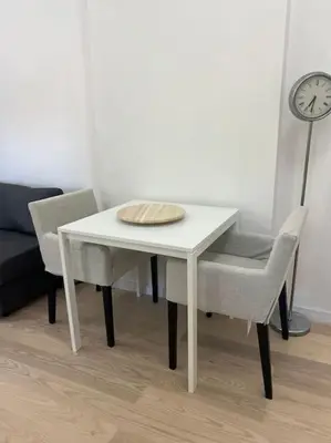 a white table with two chairs and a clock at Kopernikova Studio in Belgrade