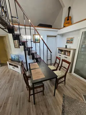 a dining room with a table and a spiral staircase at Potkrovlje Riki u centru Beograda in Belgrade
