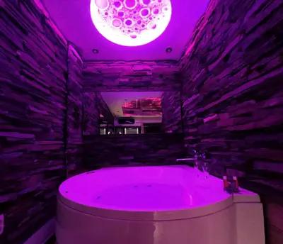 a bathroom with a large tub with a purple lighting at Stone Spa Apartman 2 in Sremčica