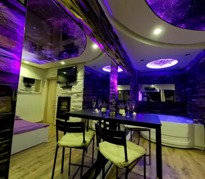 a bar with a table in a room with purple lights at Stone Spa Apartman 2 in Sremčica