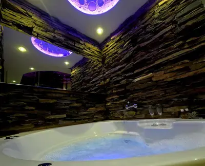 a bath tub in a room with a stone wall at Stone Spa Apartman 2 in Sremčica